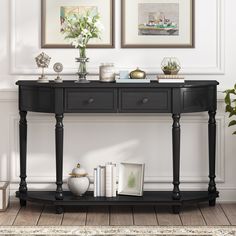 a black console table with two vases and pictures on the wall