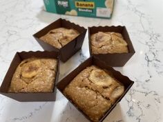 four boxes of banana muffins sitting on a counter