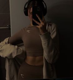 a woman with headphones on taking a selfie in front of a bathroom mirror