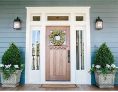 a front door with two planters and a wreath on it