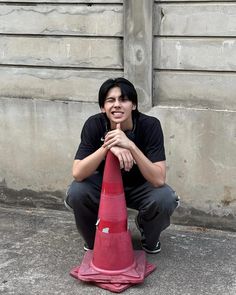 a man kneeling down next to a red traffic cone