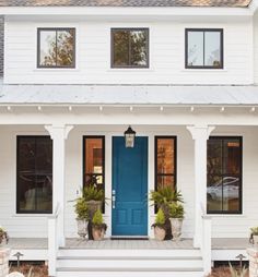 a white house with blue front door and two planters