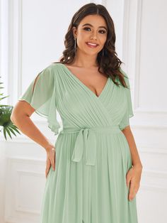 a woman in a green dress posing for the camera with her hands on her hips