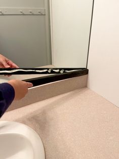 a person is brushing their teeth in front of a mirror with black and white strips on it