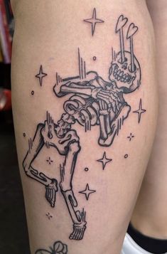 a woman's thigh with a skeleton tattoo on it and stars around her legs