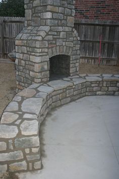 an outdoor brick oven in the middle of a yard with concrete pavers around it