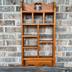 a wooden book shelf sitting next to a brick wall