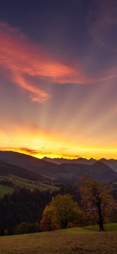 the sun is setting over some hills and trees