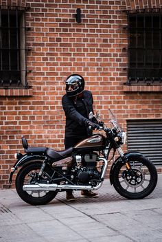 a man in black jacket and helmet standing next to motorcycle