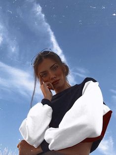 a woman is standing in the grass with her hand on her face and looking off into the distance