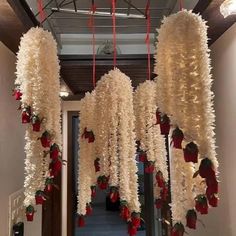 some white flowers hanging from the ceiling in a room with red and white decorations on it