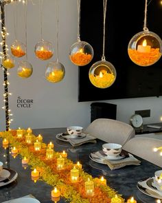 a dining room table with candles and plates on it, surrounded by hanging glass balls