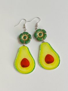 Oversized Fun & Festive Avocado Statement Earrings.  Nothing says take me to the nacho bar like these babies. Whether enjoying chips and guac or a spicy margarita these cuties will definitely represent!  Large acrylic avocado dangles with green and gold glass flower Czech bead accents.  Measuring about 3 inches in total length. Very lightweight and easy to wear. Just waiting for your next Taco Tuesday or Fiesta Friday!  Grab a pair before they're gone because as we know... Avocados don't last long! Green Novelty Earrings For Party, Green Novelty Party Earrings, Beaded Avocado, Green Fruit Design Fun Earrings, Taco Earrings, Nacho Bar, Spicy Margarita, Food Jewelry, Gold Glass