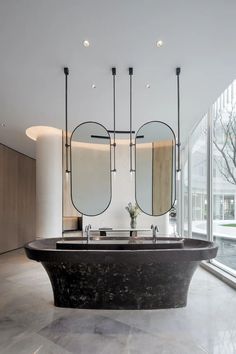 a large bath tub sitting in the middle of a room next to two mirrors on the wall