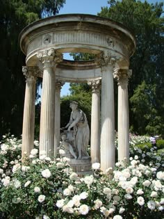 the statue is surrounded by white flowers and greenery in front of a gazebo