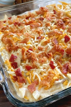 a casserole dish with cheese and bacon on it sitting on a wooden table