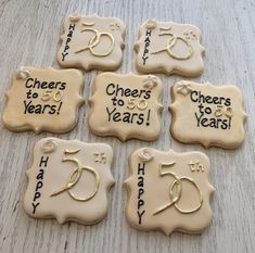 six decorated cookies that say cheers to five years and have gold numbers on them,