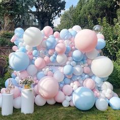 a bunch of balloons that are on the ground in front of some bushes and trees