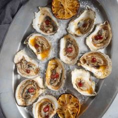 several oysters on a silver platter with lemon wedges in the middle and an orange peel