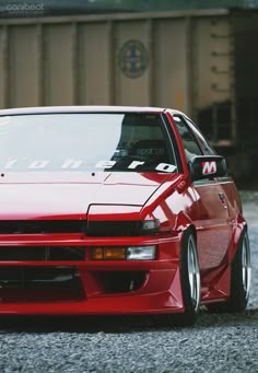 a red car parked in front of a train