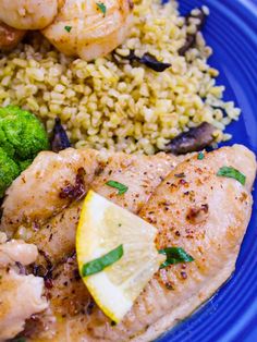 a blue plate topped with chicken, broccoli and lemon wedges next to rice