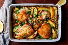 a casserole dish with chicken, potatoes and garbanzo beans on a wooden table