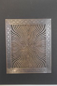 an intricately designed metal plate in a black frame