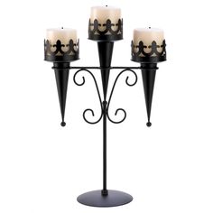 three candles are sitting on top of a metal stand with wrought iron designs and black candle holders