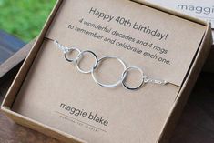 a box with a silver bracelet in it on top of a wooden table next to a card board