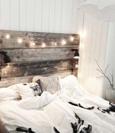 an unmade bed with white sheets and lights on the headboard is pictured in this image