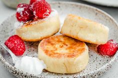 two desserts on a plate with raspberries and whipped cream in the middle