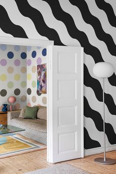 an open door leading to a living room with black and white wallpaper