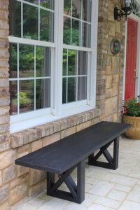 a black bench sitting in front of a window next to a planter filled with flowers