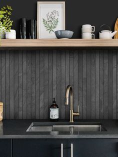 a kitchen with black counter tops and wood paneling on the wall above it is a stainless steel sink