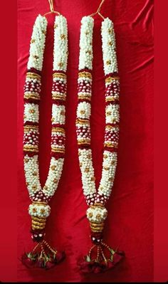 two white and red beads with tassels hanging from the ends on a red background