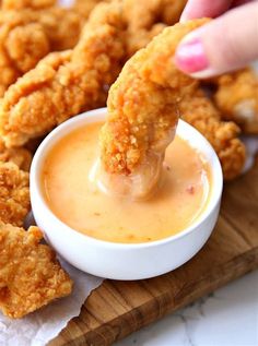 a person dipping sauce into some fried food