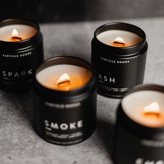 four candles with the words sparkle on them sitting next to each other in black tins