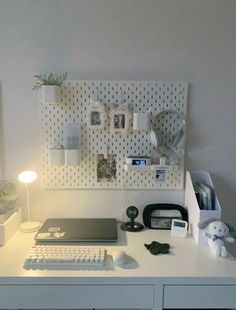 a white desk topped with a laptop computer next to a lamp and other office supplies