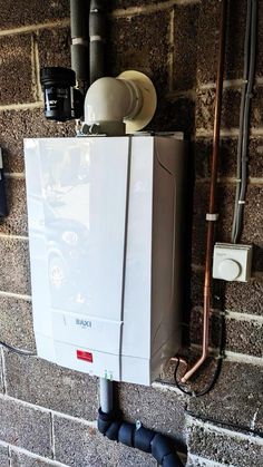 a tank mounted to the side of a brick wall next to a water heater