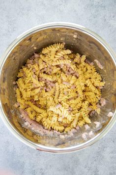 a metal bowl filled with pasta and meat