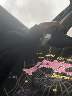 a person sitting in the drivers seat of a car wearing a t - shirt with an image on it