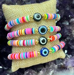 "🌈This listing is for One Rainbow Evil Eye Handmade Heishi Beaded Bracelet. These bracelets fit wrist sizes on average 7-8\".  🧿The evil eye is a symbol of spiritual protection. Dating back thousands of years and seen in many different cultures, the evil eye is known to ward off negativity by sending it back to the person who sent it.  The Evil Eye Charm on this bracelet is available in 2 colors:  Blue or Black  **Due to the unique nature of each stone, your item may vary slightly from the picture shown. All items are cleansed with white sage before being shipped. Any comments, questions, or concerns feel free to contact me, I am here to help!" Bohemian Multicolor Heishi Beads Bracelets, Colorful Heishi Beaded Bracelets For Festivals, Multicolor 8mm Bead Wristband Gift, Multicolor 8mm Beads Wristband For Gift, Pink Beaded Evil Eye Bracelet With Round Beads, Handmade Pink Evil Eye Bracelet With Round Beads, Multicolor Friendship Bracelets With Spacer Beads For Festival, Multicolor Round Beads Friendship Bracelets For Festivals, Pink Beaded Evil Eye Bracelet