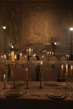 a table set with plates and candles in an old style dining room at a wedding