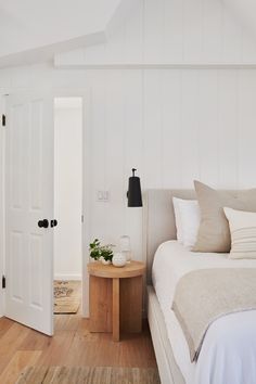 a bed sitting in a bedroom next to a wooden table and white walls with two doors