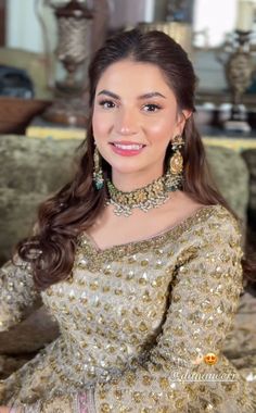 a woman sitting on top of a couch wearing a dress and jewelry in her hand