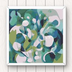 a cross stitch pattern with green and white flowers on it, hanging on a wall