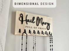 a wooden sign that says hall mary full of grace with black beads hanging from it