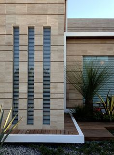 a modern house with wood and glass panels on the front door, along with landscaping