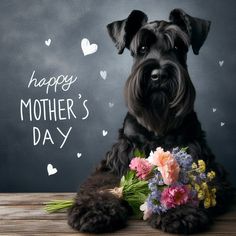 a black dog sitting on top of a wooden table next to a bouquet of flowers