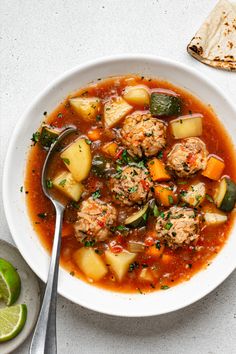 a white bowl filled with meat and vegetable soup next to a tortilla shell